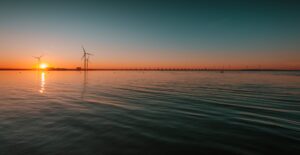 Services beautiful view of the calm ocean with turbines under the mesmerizing sunset in the background